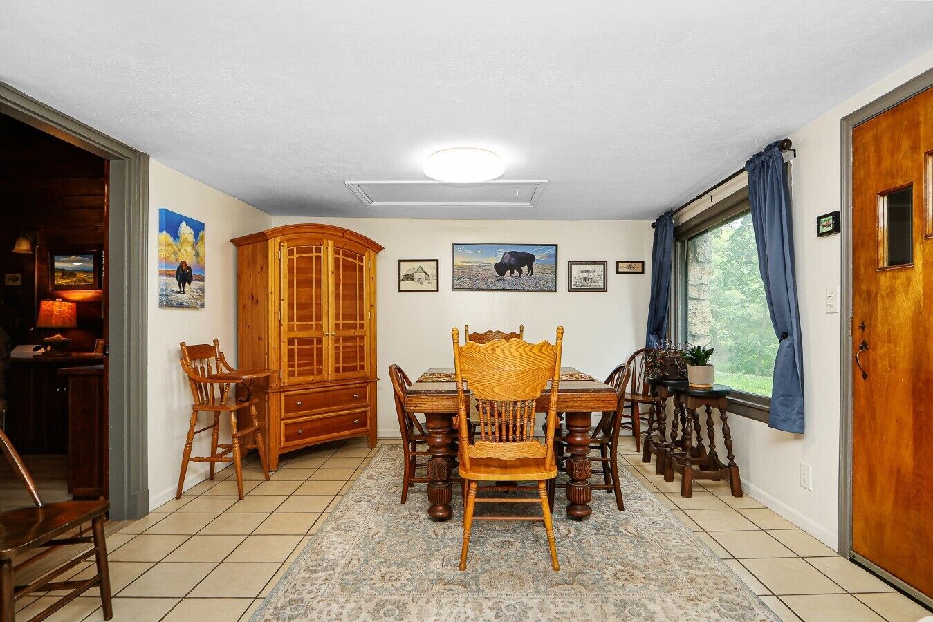 A dining area with a wooden table and chairs, a cabinet, and a rug.