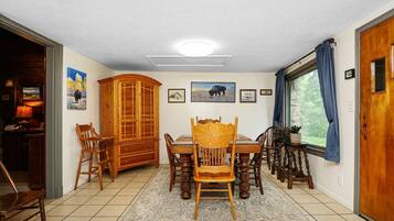 A dining area with a wooden table and chairs, a cabinet, and a rug.