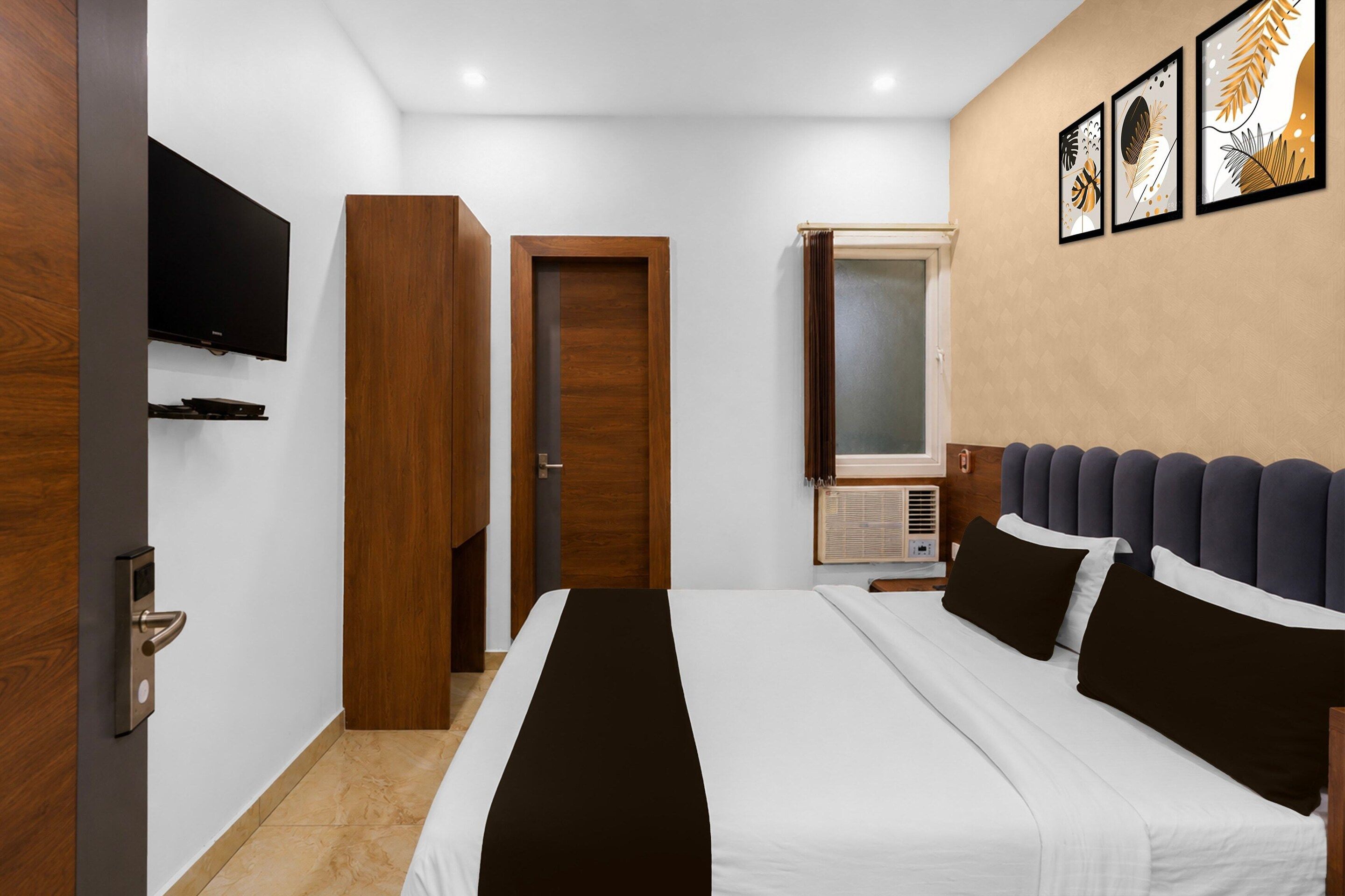 A hotel room with a bed, a television, a wardrobe, a door, and a window.