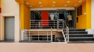 A building entrance with a staircase leading to a second floor, a glass door, and a mannequin in a shop window.
