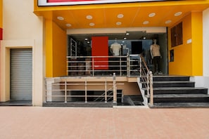 A building entrance with a staircase leading to a second floor, a glass door, and a mannequin in a shop window.