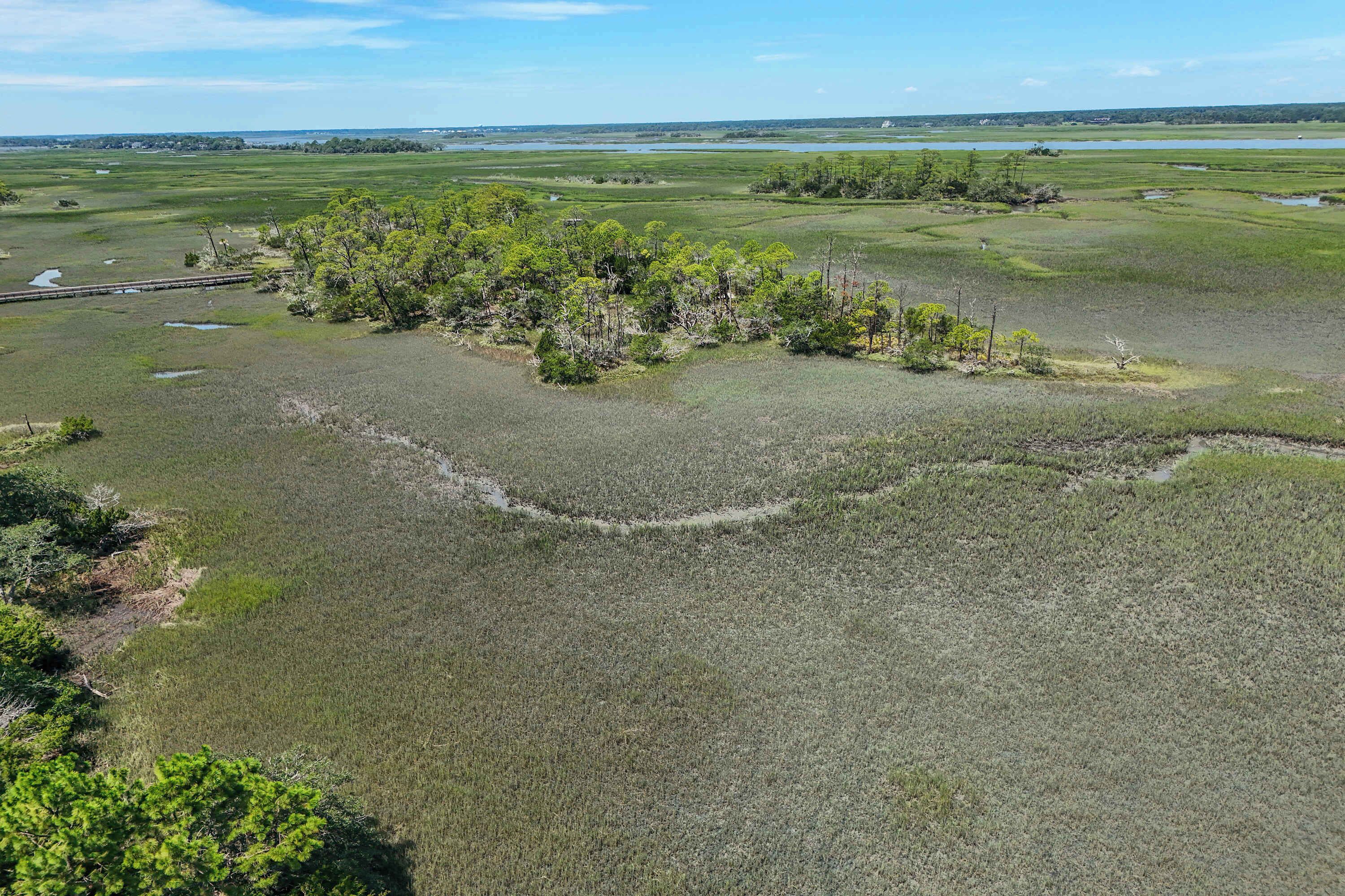 An aerial view of a coastal landscape with a small island of trees surrounded by water.