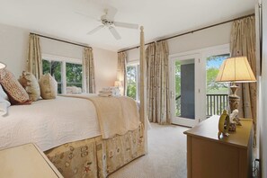 Ein Schlafzimmer mit einem Bett, einem Deckenventilator, einem Fenster und einer Tür zu einem Außenbereich.