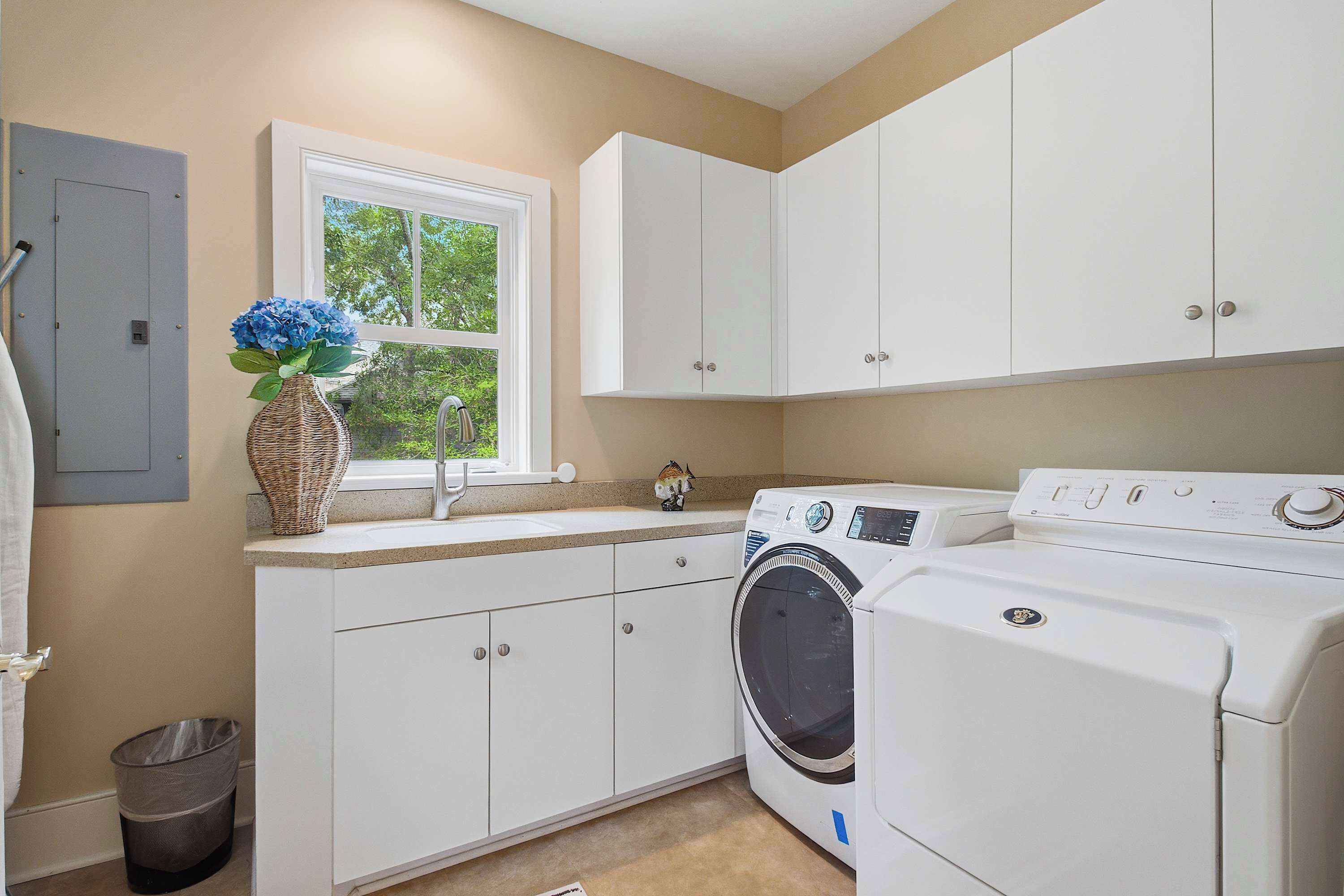 A laundry room with a washing machine, a sink, and cabinets.