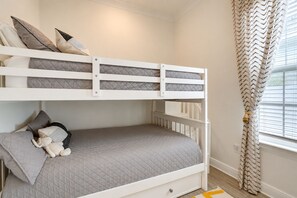 Un lit superposé avec un matelas matelassé gris, des oreillers et un jouet en peluche.