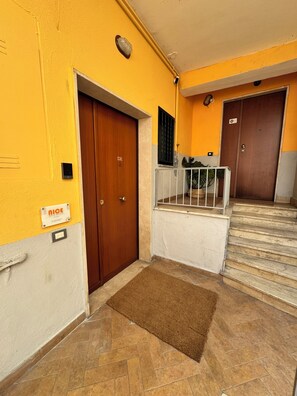A hallway with a wooden door, a metal gate, and a staircase leading to another door. - An elegant open-concept space in Salerno's harbor area, just a short walk from downtown. (Salerno)