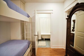 Un dormitori amb un llit superposat, un armari i un bany visible a través d'una porta oberta.