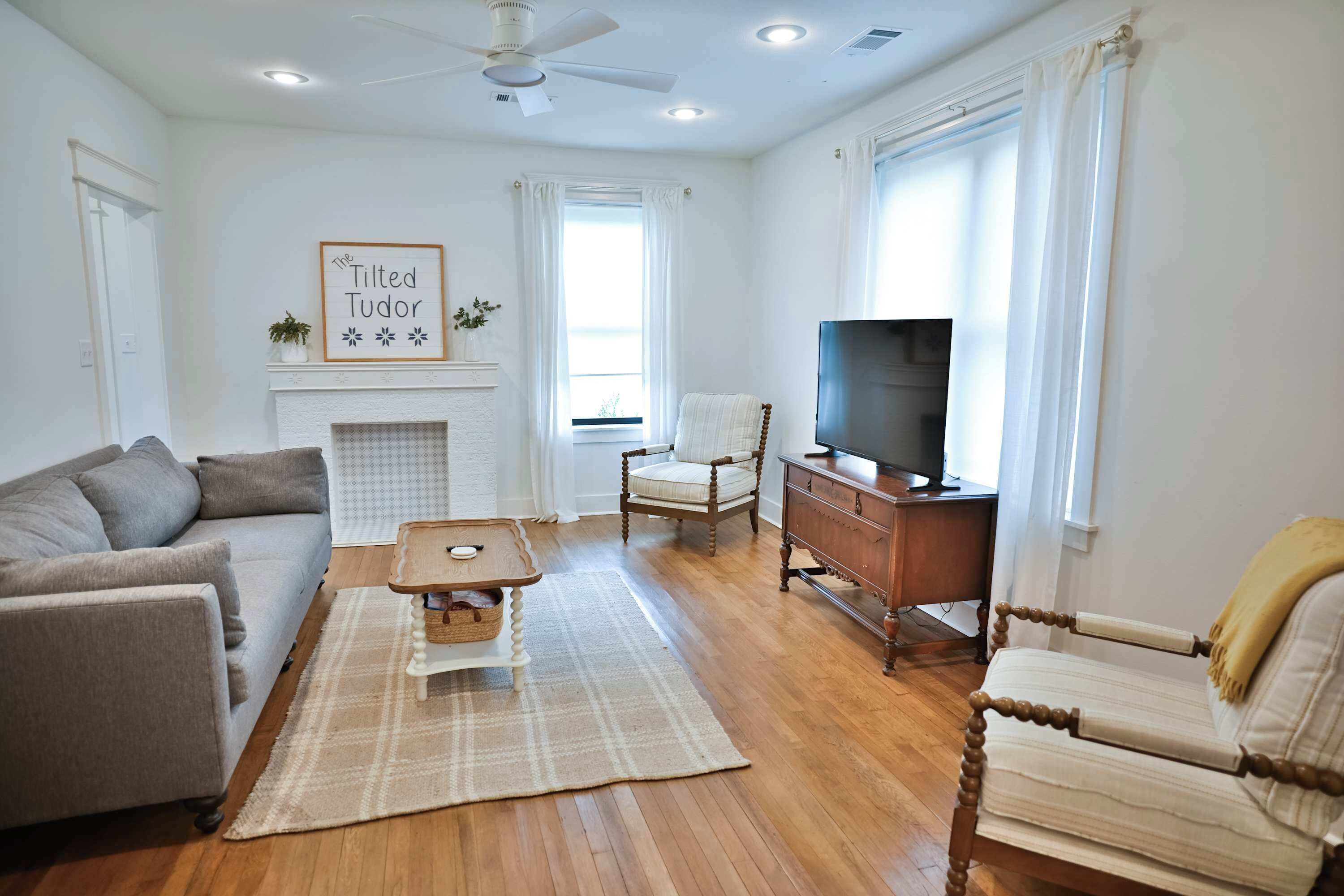 Een woonkamer met een bank, salontafel, tv-meubel en een open haard.
