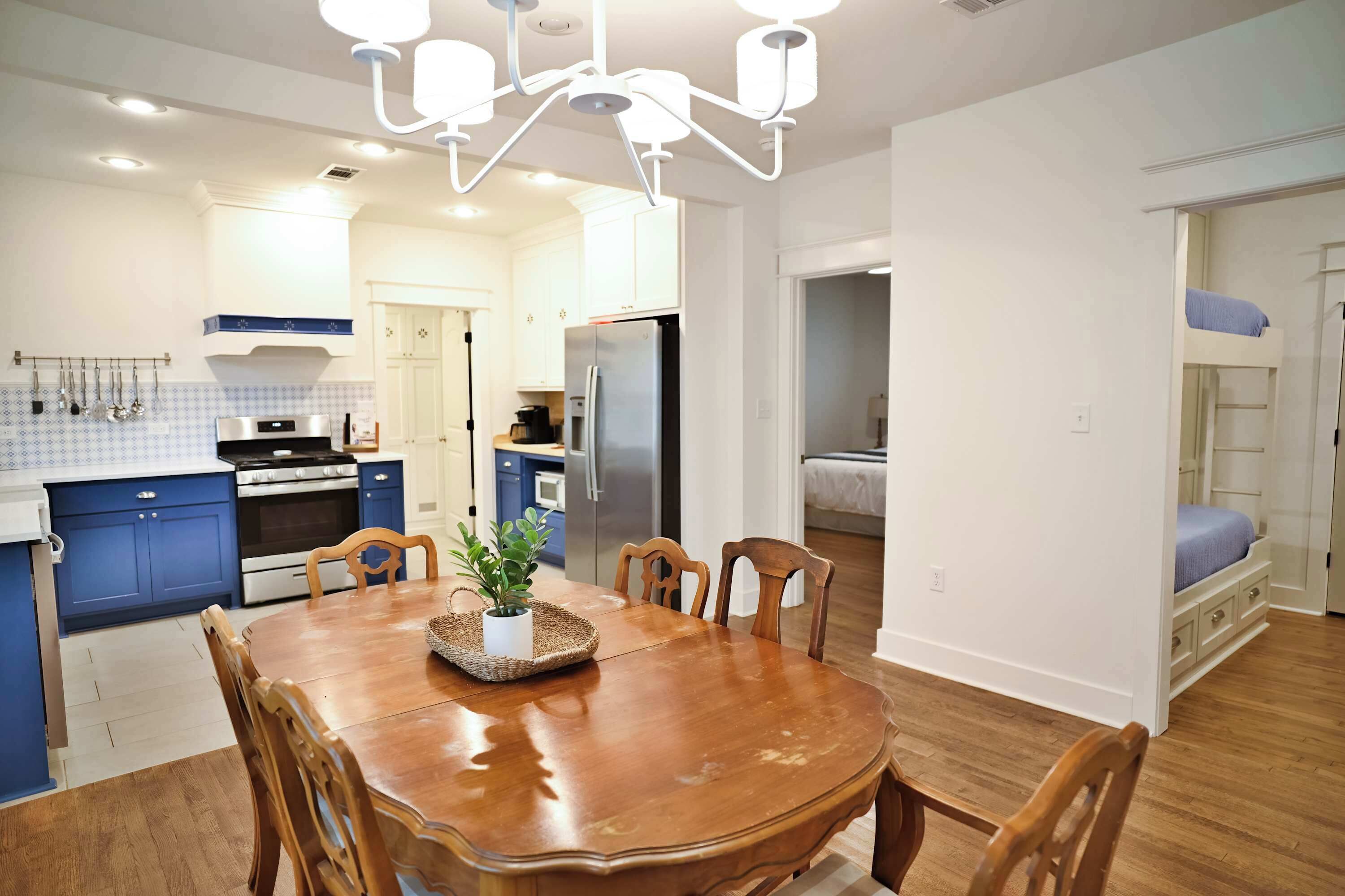 A modern kitchen with a dining table, chairs, and a chandelier.