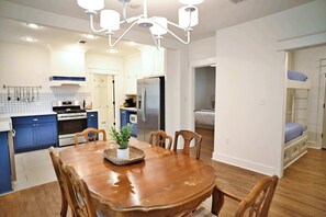 A modern kitchen with a dining table, chairs, and a chandelier.