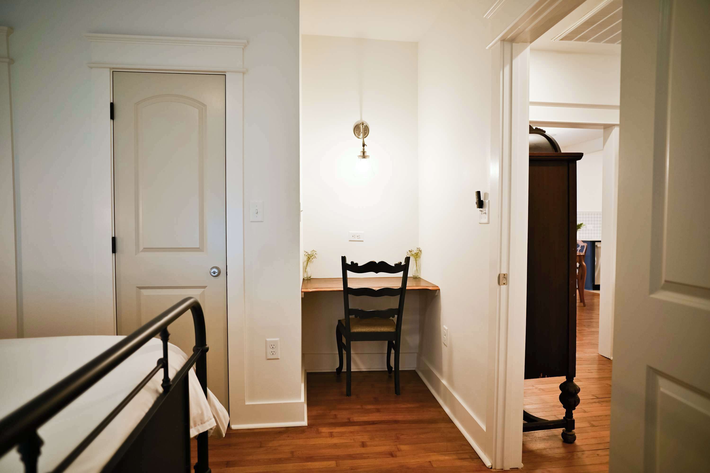 Un pasillo con una puerta, una silla y una mesa con un jarrón.
