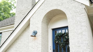 Een gebouw met een witte bakstenen gevel, een blauwe deur en een wandlamp.