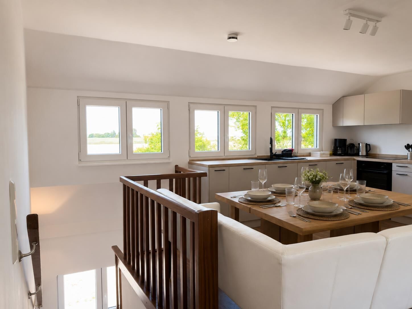 Una cocina moderna con comedor, ventanas amplias y una escalera.