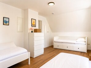 A bedroom with a white bed, a white dresser, a white nightstand, and a white wardrobe. - "Weite" Vacation Rental in Wangerland for up to 5 people – 80 m², 2 bedrooms, modern amenities, quiet location, and dogs welcome. (Wangerland)