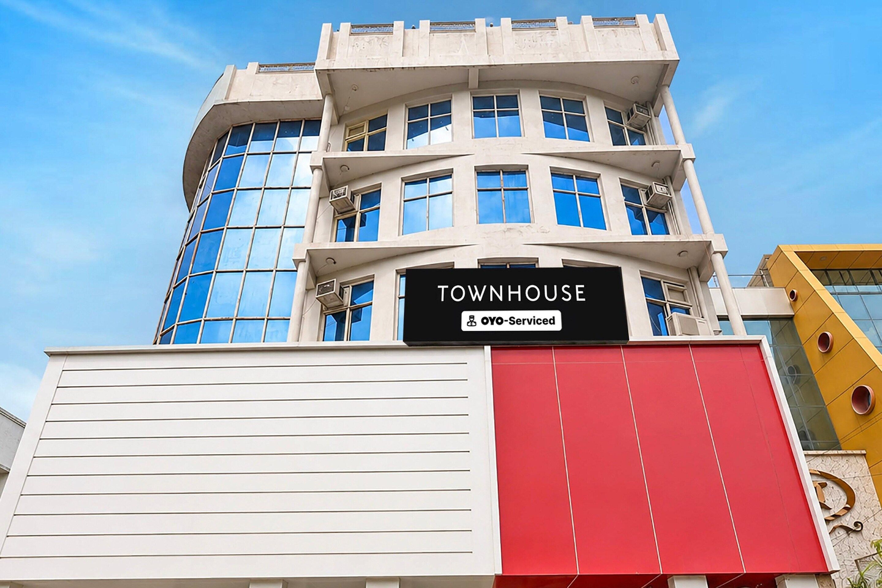 A multi-story building with a sign reading 'TOWNHOUSE' and 'OYO-Serviced'.
