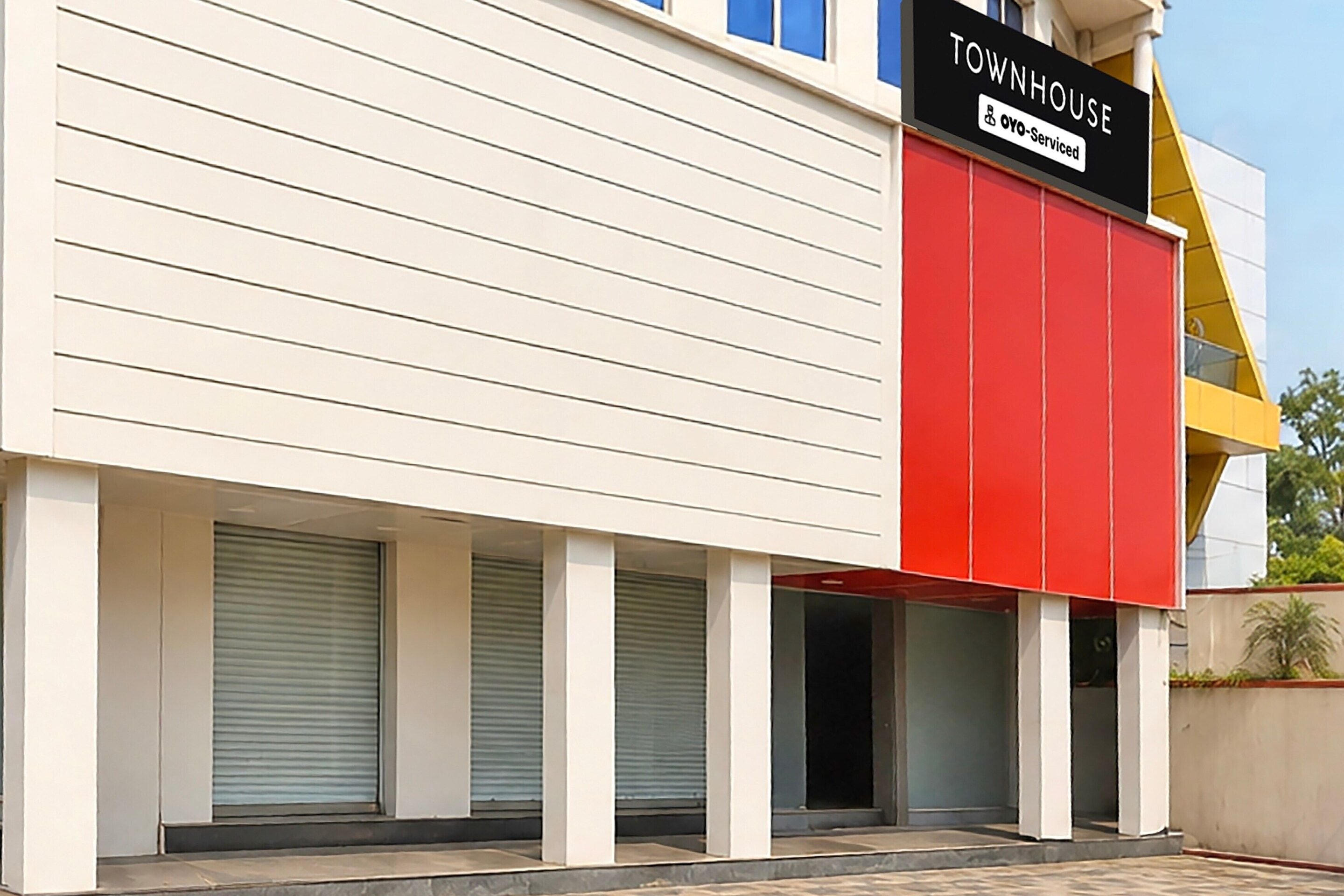 Un immeuble avec une enseigne indiquant « TOWNHOUSE » et « Oyo-Serviced ». Les volets du rez-de-chaussée sont fermés.