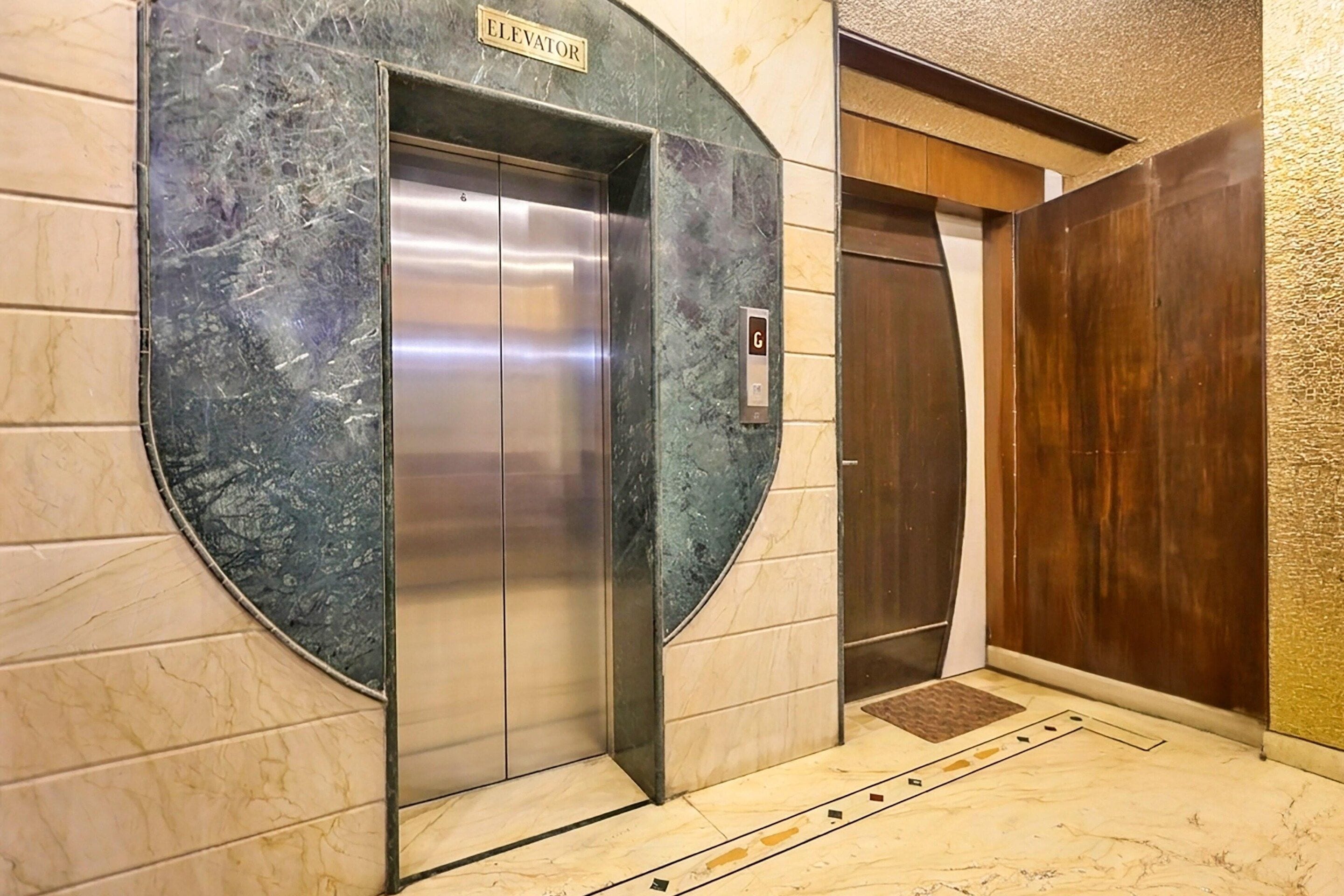 An elevator with a marble wall and a wooden door.