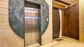 An elevator with a marble wall and a wooden door.