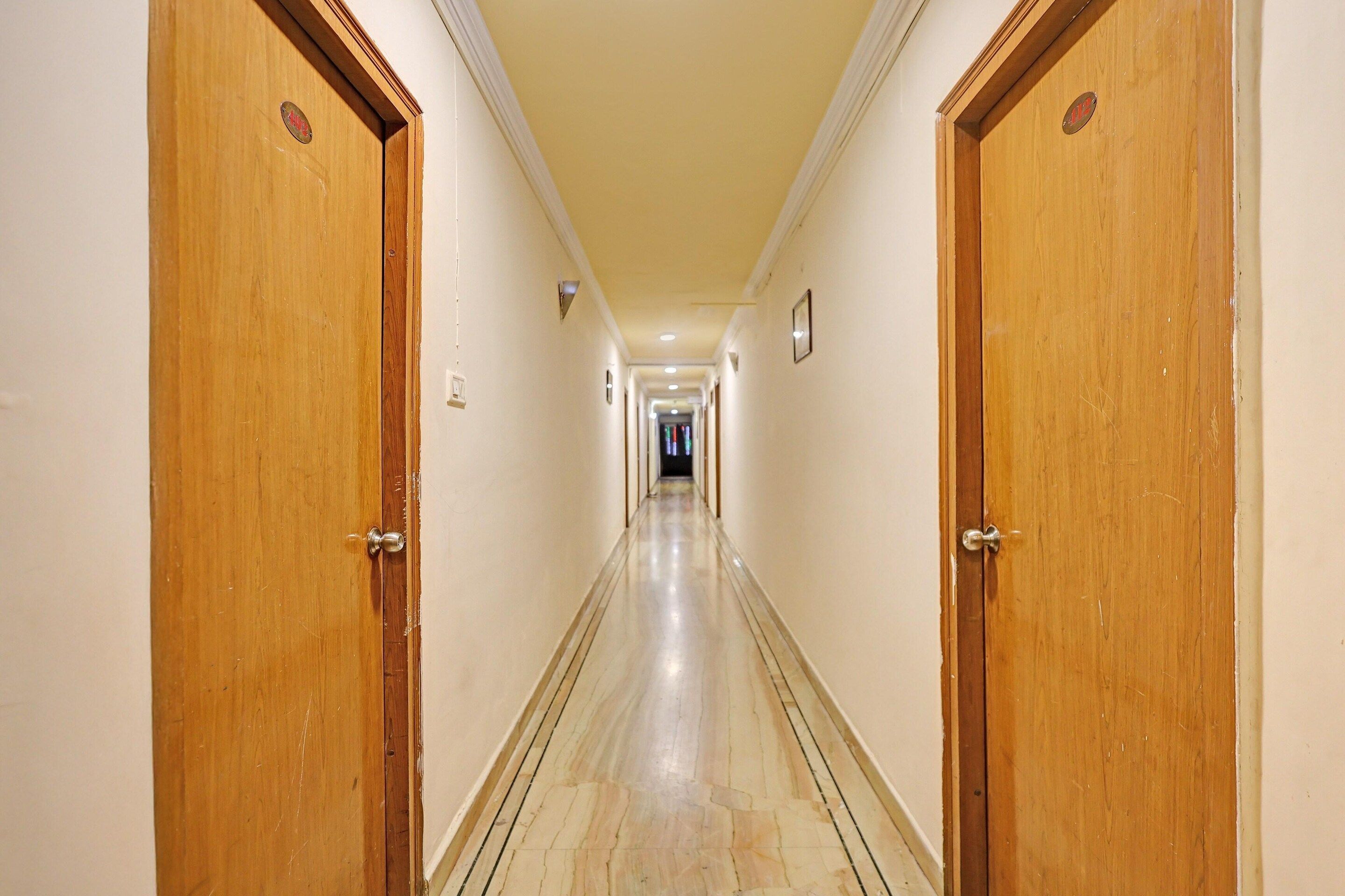 A hotel hallway with wooden doors, a tiled floor, and a light-colored wall.