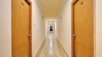 A hotel hallway with wooden doors, a tiled floor, and a light-colored wall.
