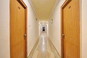 Un pasillo de hotel con puertas de madera, piso de baldosas y pared de color claro.