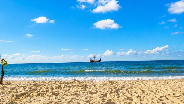 A beach with a boat in the distance, clear skies, and calm sea. - Studio for 2 People, Close to the sea (Kamien Pomorski)