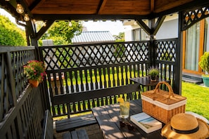 A wooden deck with a bench, a table with a basket and a book, and a potted plant. - Studio for 2 People, Close to the sea (Kamien Pomorski)