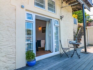 A house with a wooden deck, a potted plant, and a table with chairs. - Shipwrights (Brixham)