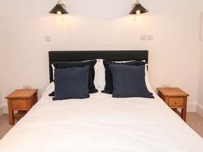 A bed with a black headboard, two bedside tables, and two wall-mounted lamps. - Shipwrights (Brixham)
