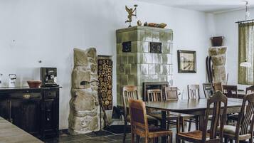 A dining area with a stone wall, a tiled fireplace, and a table set for four.