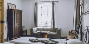 Habitació d'hotel amb un llit, una cadira, un armari i una finestra amb cortines.