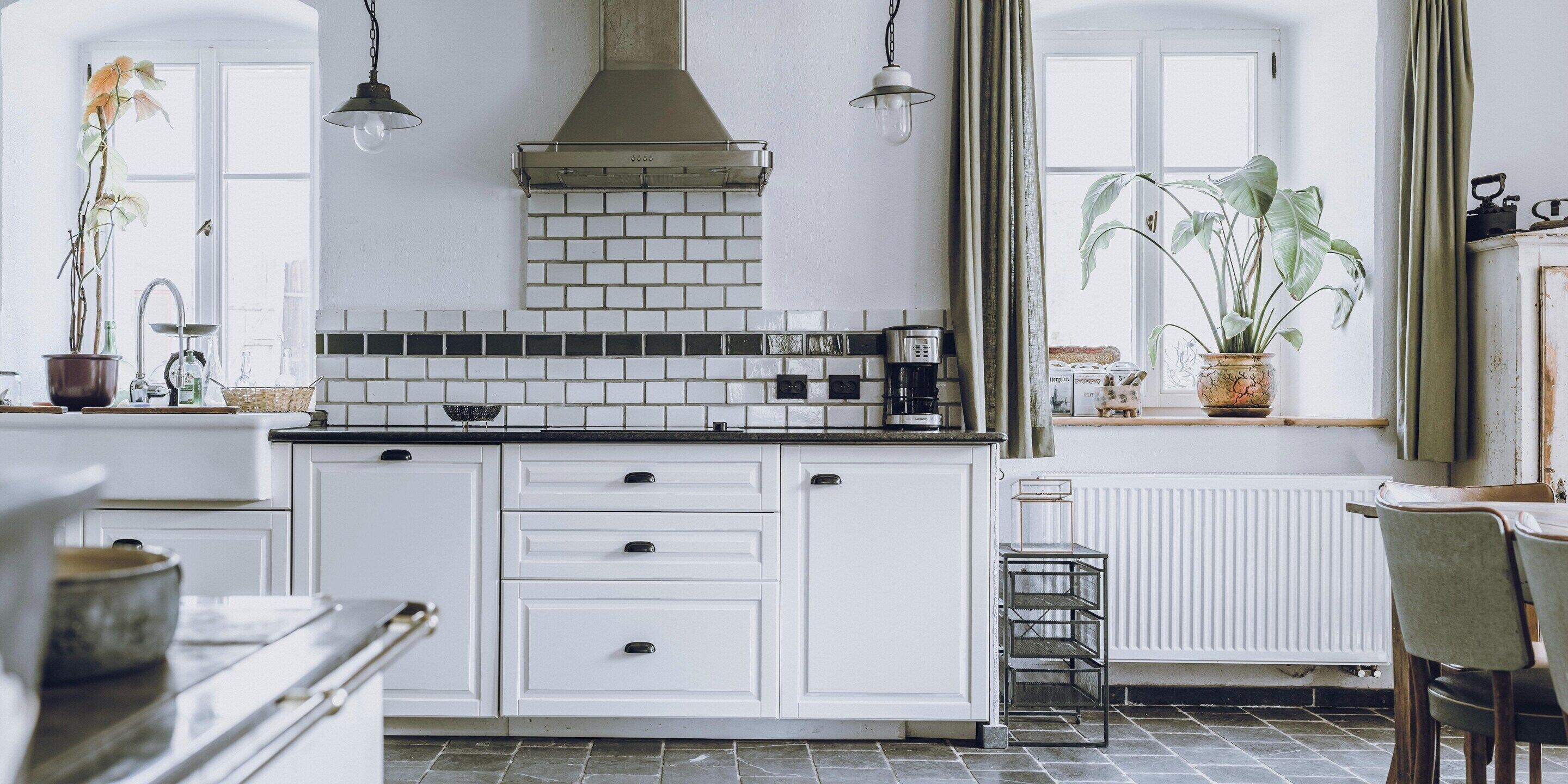 Cocina con armarios blancos, encimera negra y salpicadero de azulejos.