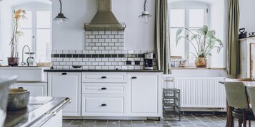 Cocina con armarios blancos, encimera negra y salpicadero de azulejos.