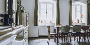 Uma área de refeições com mesa e cadeiras, um radiador e uma janela com cortinas.