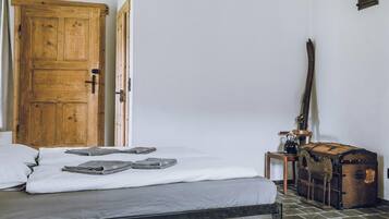 A room with a bed, a wooden door, a suitcase, and a lamp.