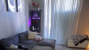 A modern living room with a sectional sofa, a small black chair, and a wooden floor. - 3/2bth Supercondo in delightful Las Vegas with full gym, jacuzzi n pool for you! (Las Vegas)