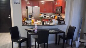 A modern kitchen with red cabinets, a central island, and a dining area with four chairs. - 3/2bth Supercondo in delightful Las Vegas with full gym, jacuzzi n pool for you! (Las Vegas)