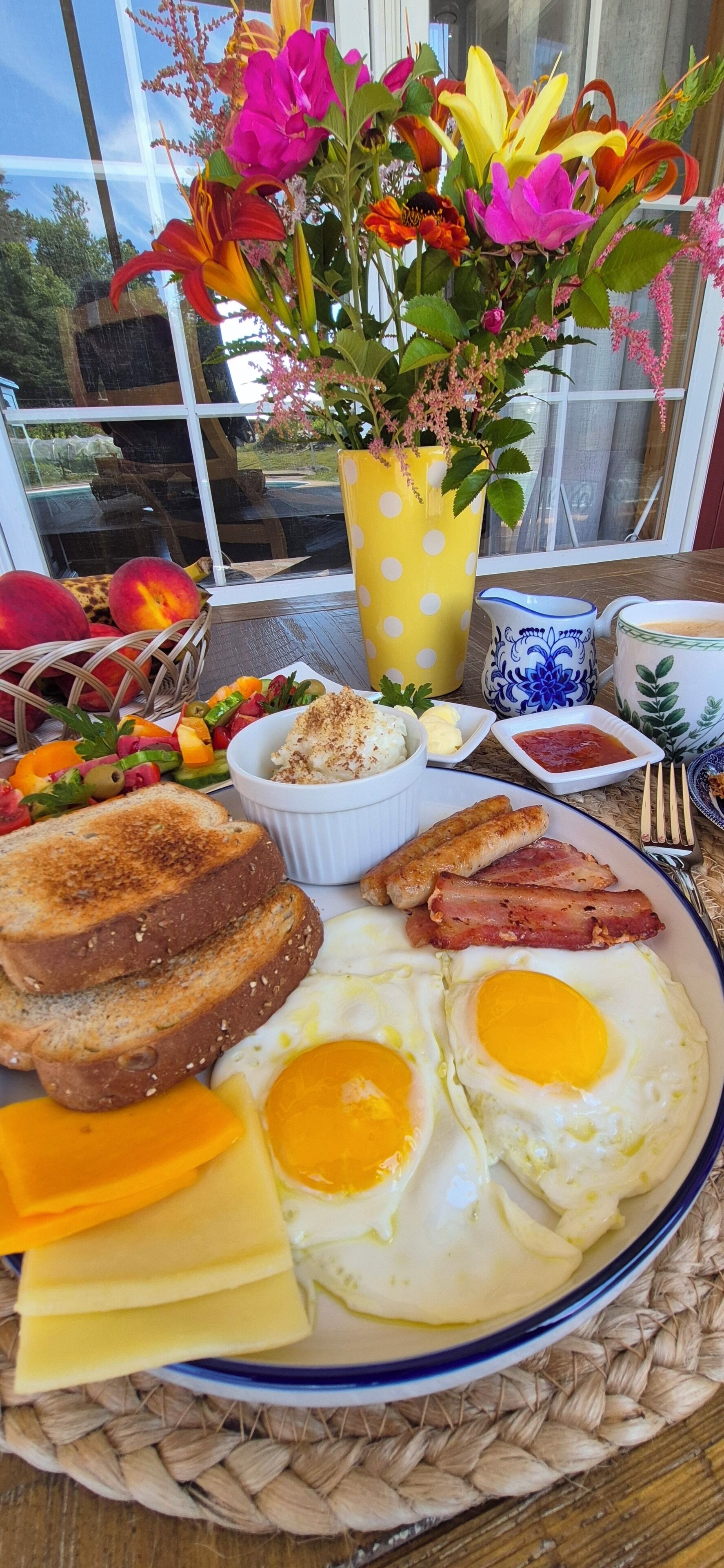 Ein Frühstückstisch mit Eiern, Toast, Käse und einem Obstsalat.