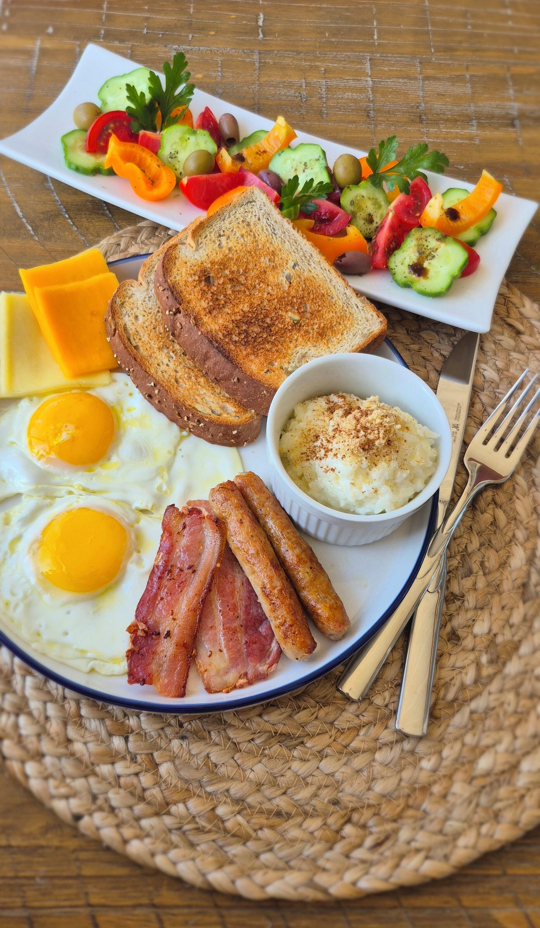 Un plato de desayuno con huevos, tocino, tostadas, queso y una ensalada.