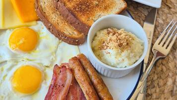 Un plato de desayuno con huevos, tocino, tostadas, queso y una ensalada.
