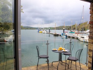 A dining area with a table and chairs overlooking a marina with boats. - Spanish Boathouse (Brixham)