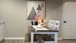 Un comedor con una mesa y sillas, un cuadro en la pared y una puerta al fondo.