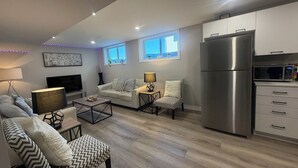 Una sala de estar moderna con un sofá, un sillón, una mesa de centro y un televisor de pantalla plana.