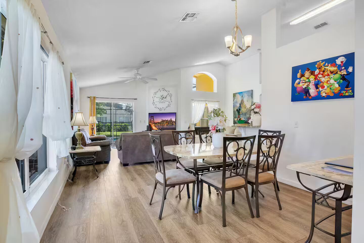 A dining area with a round table and chairs, a sofa, and a ceiling fan.