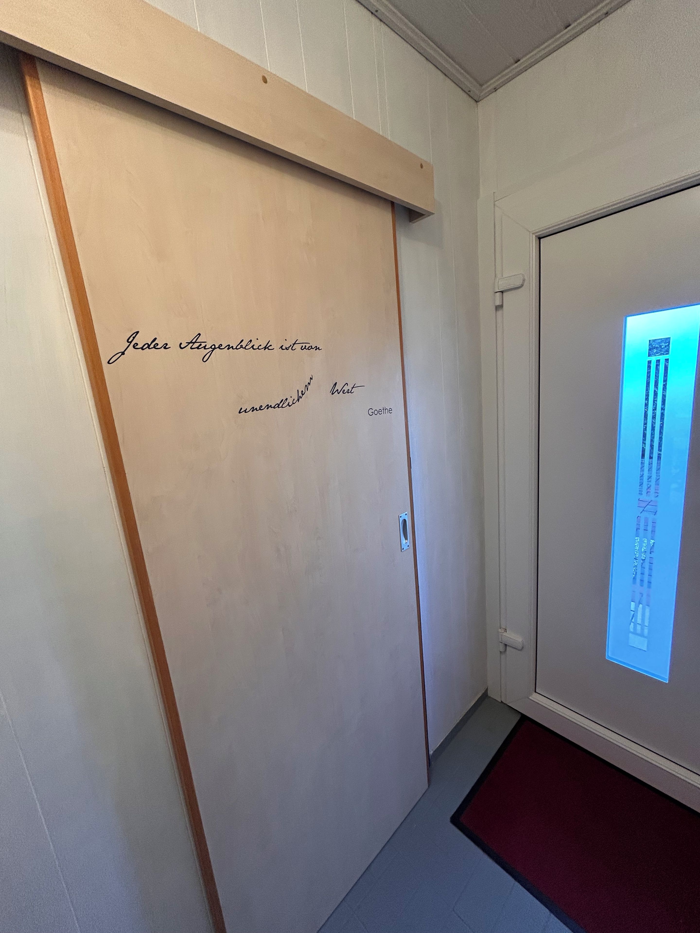 Ein Zimmer mit einer Schiebetür, einem Holzrahmen und einem wandmontierten Bildschirm.