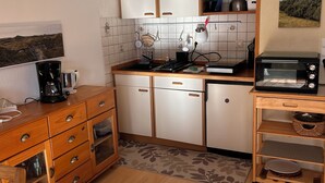 A compact kitchen with white cabinets, a wooden countertop, a coffee maker, a kettle, and a toaster.