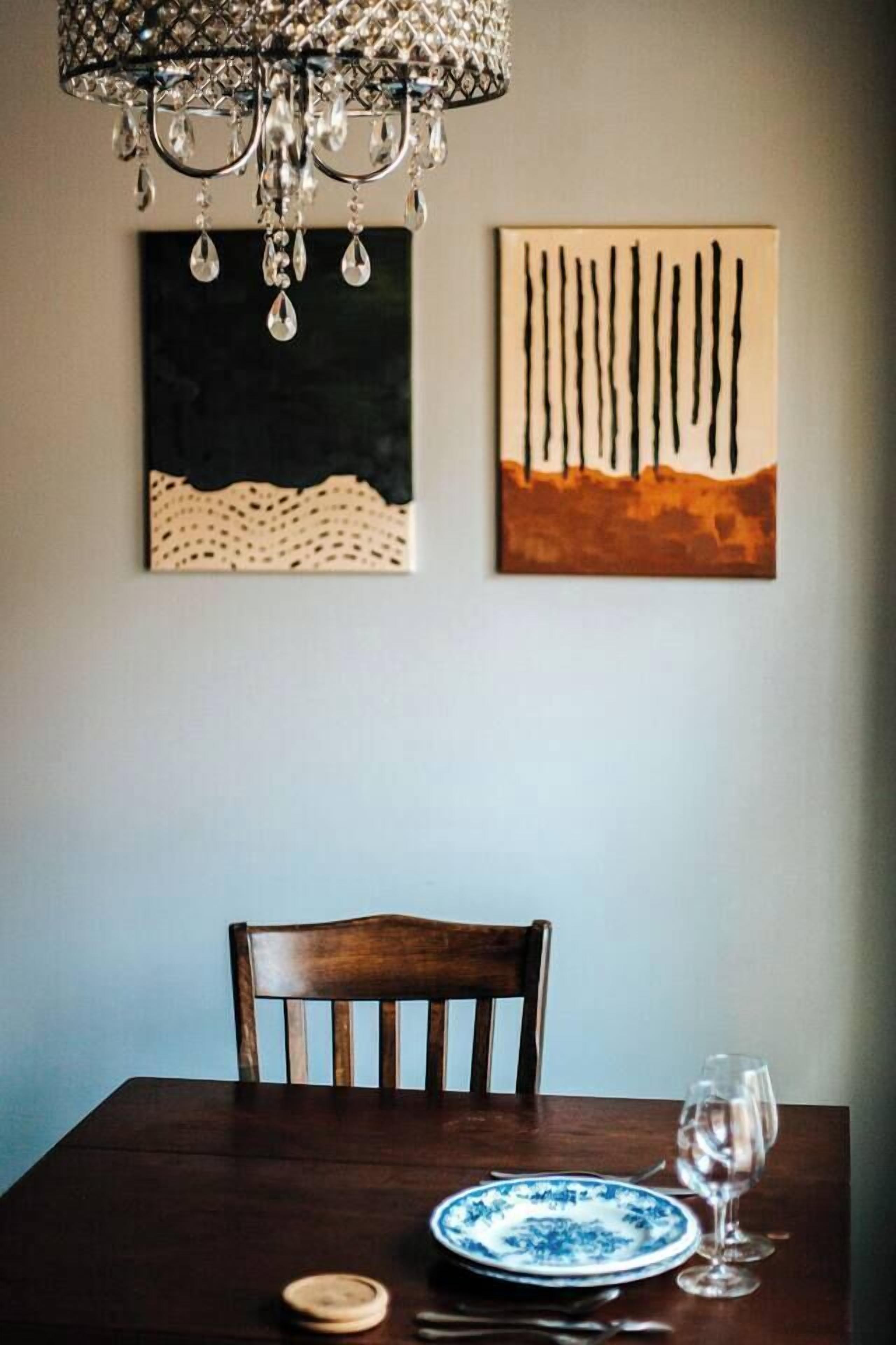 A dining table with a chair, a plate, a glass, and a candle. There is a chandelier above the table.