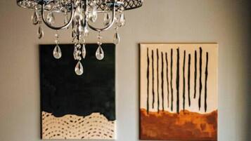 A dining table with a chair, a plate, a glass, and a candle. There is a chandelier above the table.