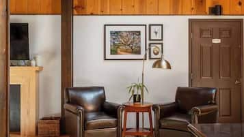A wooden-paneled room with two leather chairs, a small table with a plant, and a door.