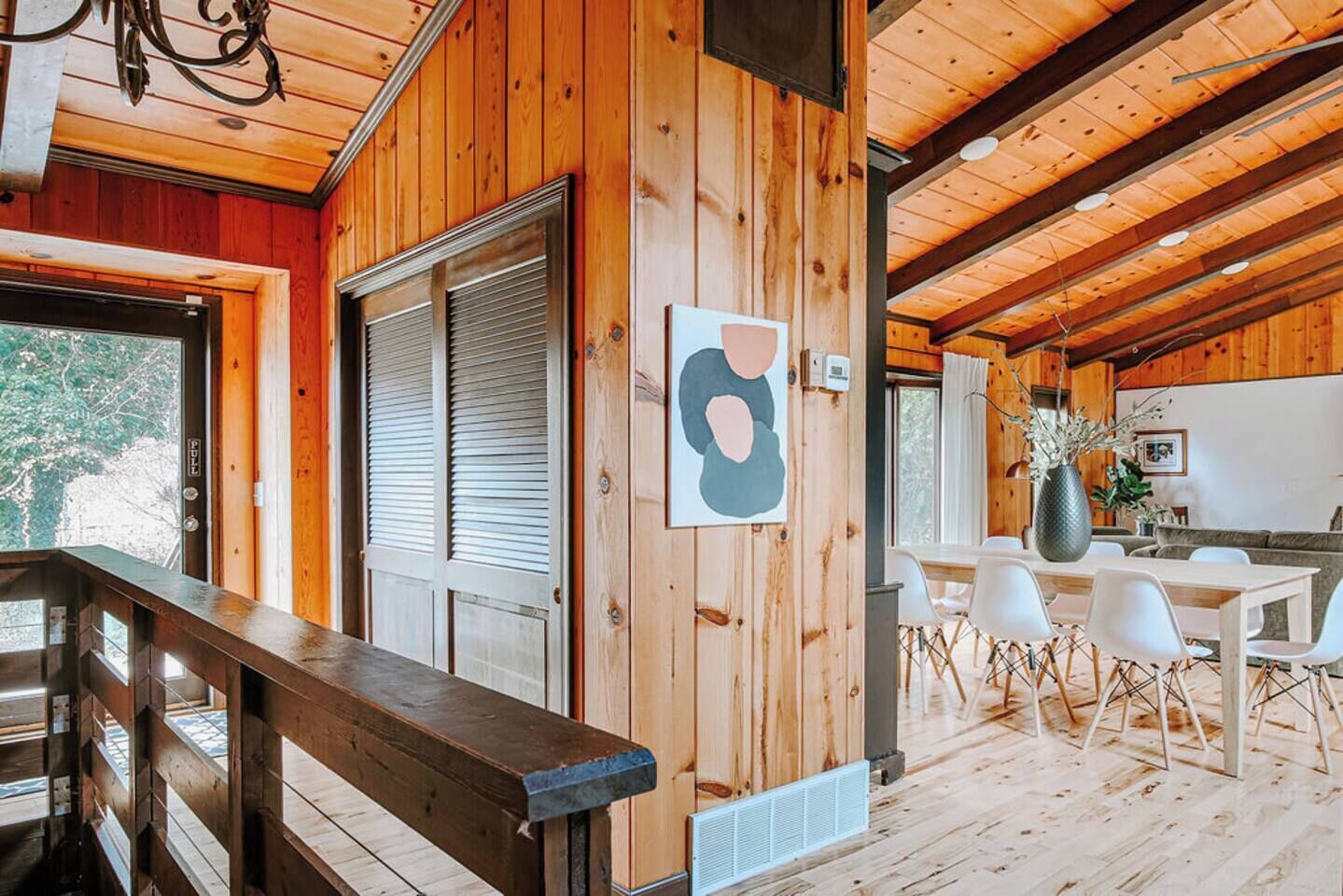 Un intérieur en bois comprenant un coin repas, une grande fenêtre et un escalier.